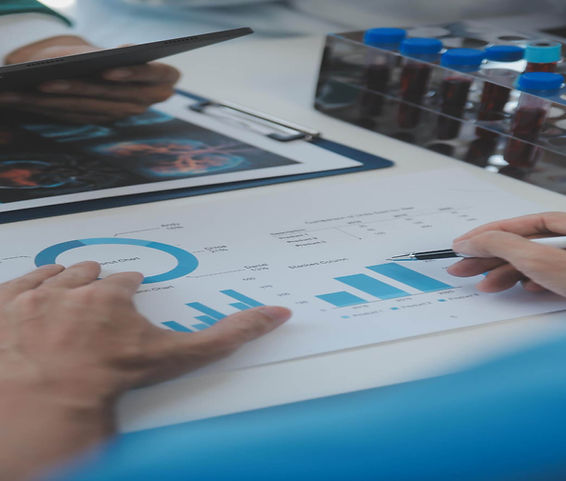 Healthcare data operations planning session with charts, tablet, and clinical materials.